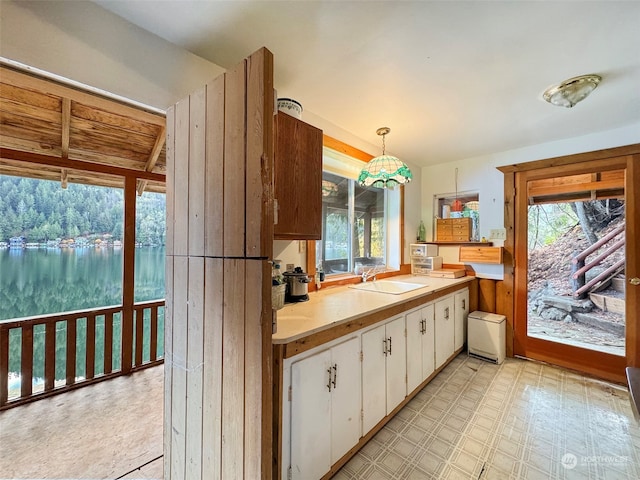 kitchen featuring sink, white cabinets, and hanging light fixtures