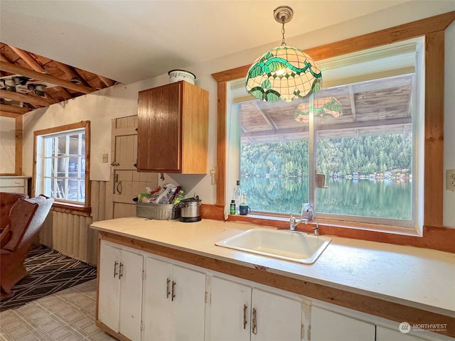 kitchen featuring sink, white cabinetry, and hanging light fixtures