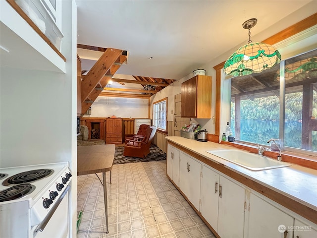 kitchen featuring white range with electric cooktop, sink, white cabinets, and decorative light fixtures