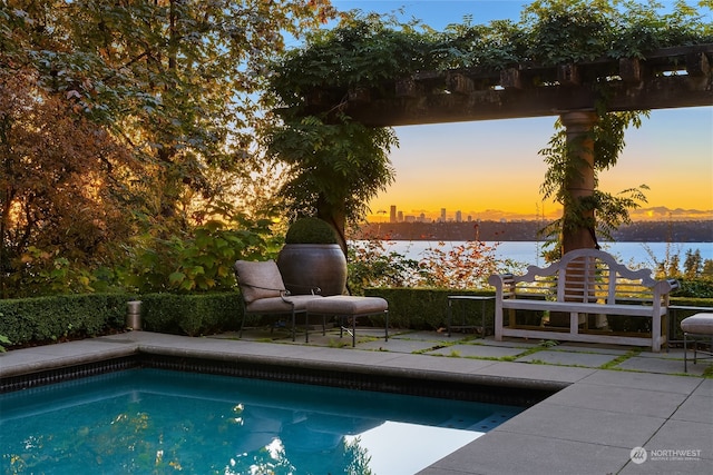 pool at dusk with a patio and a water view