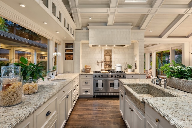 kitchen with white cabinetry, sink, light stone countertops, tasteful backsplash, and range with two ovens