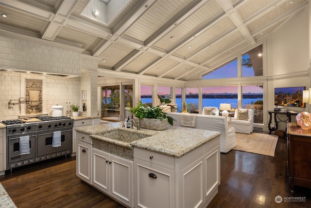 kitchen featuring vaulted ceiling with beams, white cabinetry, double oven range, and light stone counters