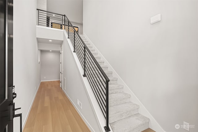 staircase featuring a towering ceiling and wood-type flooring