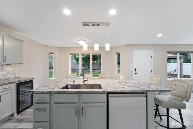 kitchen with wine cooler, decorative backsplash, an island with sink, and decorative light fixtures