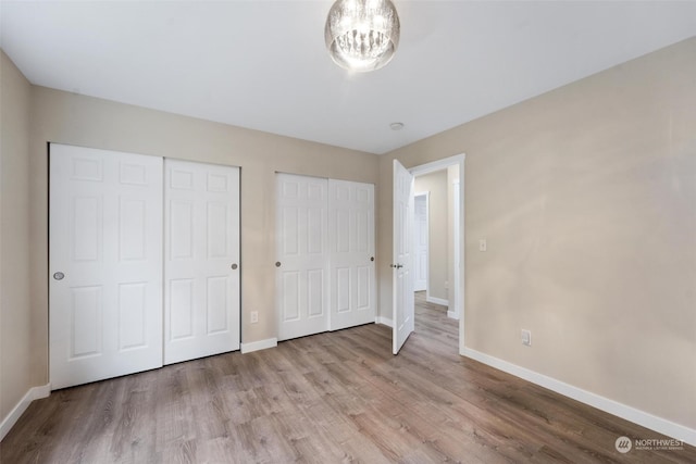 unfurnished bedroom featuring multiple closets and light hardwood / wood-style flooring