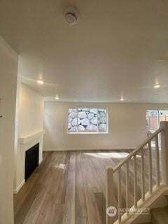 unfurnished living room with baseboards, recessed lighting, wood finished floors, and a fireplace