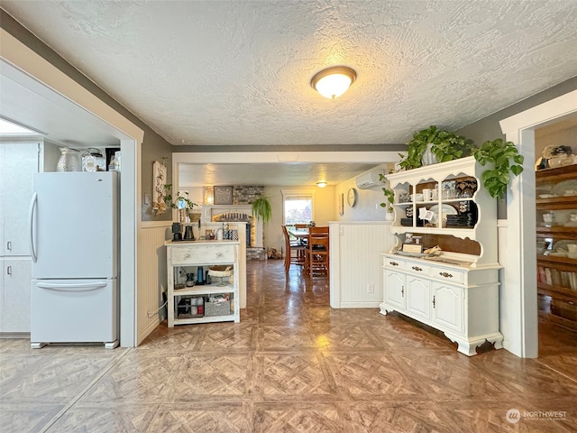 kitchen featuring light parquet floors, a textured ceiling, white refrigerator, and a wall unit AC