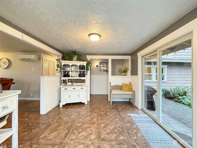 kitchen with a wall mounted air conditioner, a textured ceiling, and parquet floors