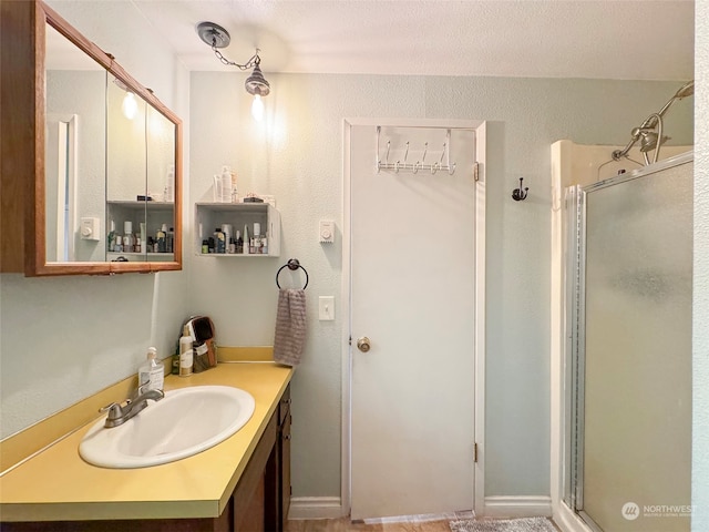 bathroom featuring vanity, a shower with shower door, and a textured ceiling