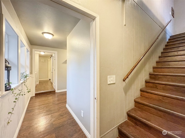 staircase with a textured ceiling and hardwood / wood-style flooring