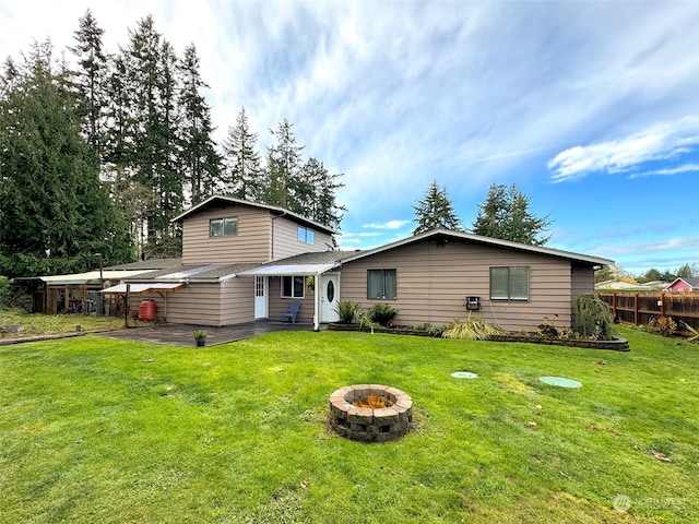 rear view of property with a fire pit, a patio, and a lawn