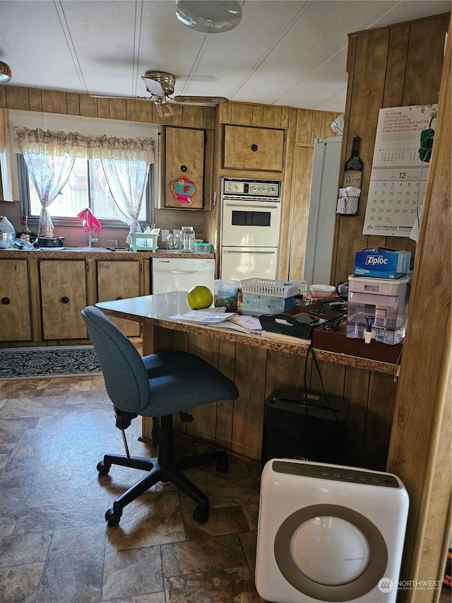 kitchen with white appliances, ceiling fan, and wood walls