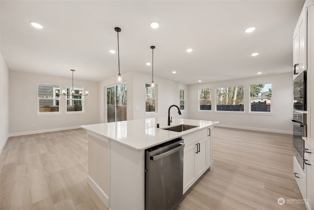 kitchen with sink, decorative light fixtures, appliances with stainless steel finishes, a kitchen island with sink, and white cabinets