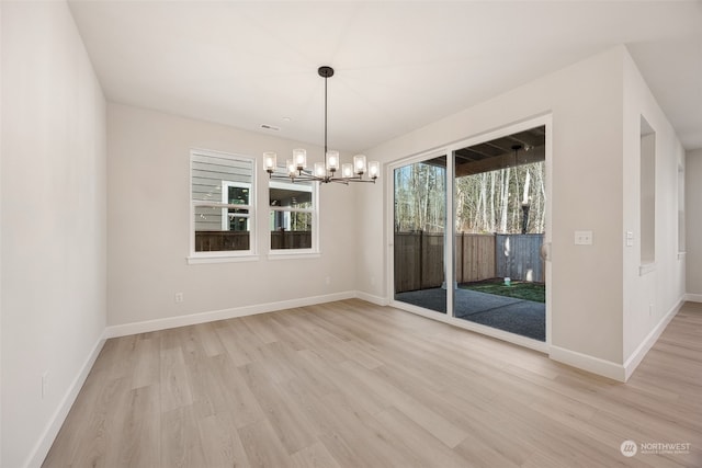 unfurnished dining area featuring a chandelier and light hardwood / wood-style floors