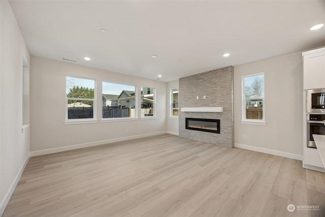 unfurnished living room with plenty of natural light, a fireplace, and light hardwood / wood-style floors