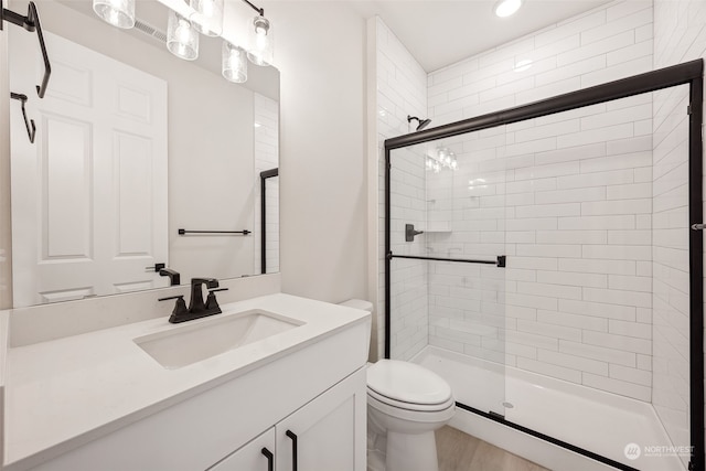 bathroom featuring toilet, vanity, and a shower with shower door