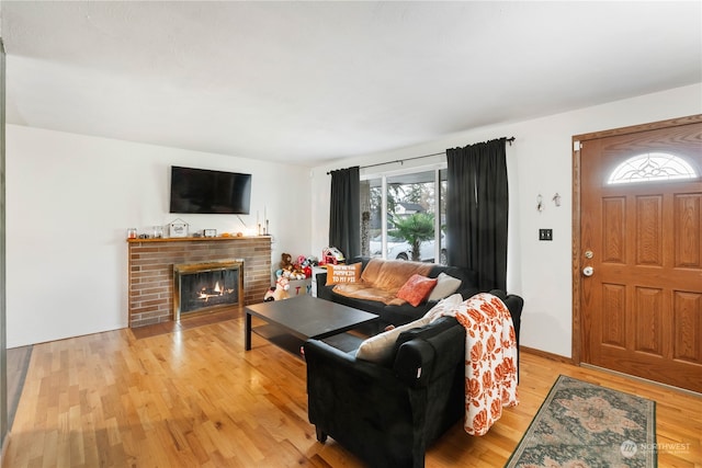 living room featuring light hardwood / wood-style flooring and a brick fireplace