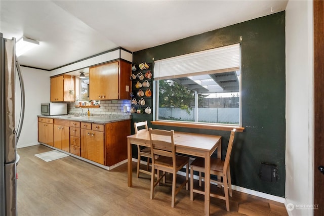 1522 Wheeler St S, Tacoma, WA 98444 - kitchen with stainless steel appliances, light wood-style floors, backsplash, a sink, and brown cabinets