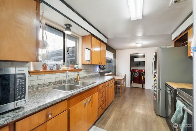 1522 Wheeler St S, Tacoma, WA 98444 - kitchen featuring separate washer and dryer, stainless steel microwave, a sink, light wood finished floors, and tasteful backsplash