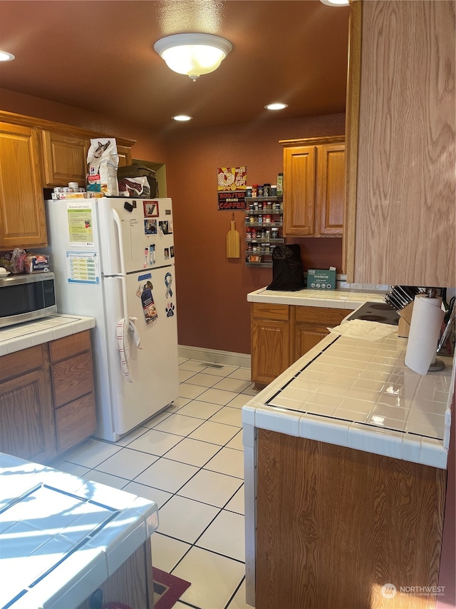 kitchen with tile countertops, white fridge, and light tile patterned flooring