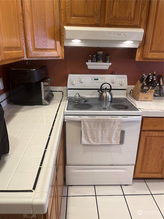 kitchen featuring tile countertops, light tile patterned floors, and white electric range