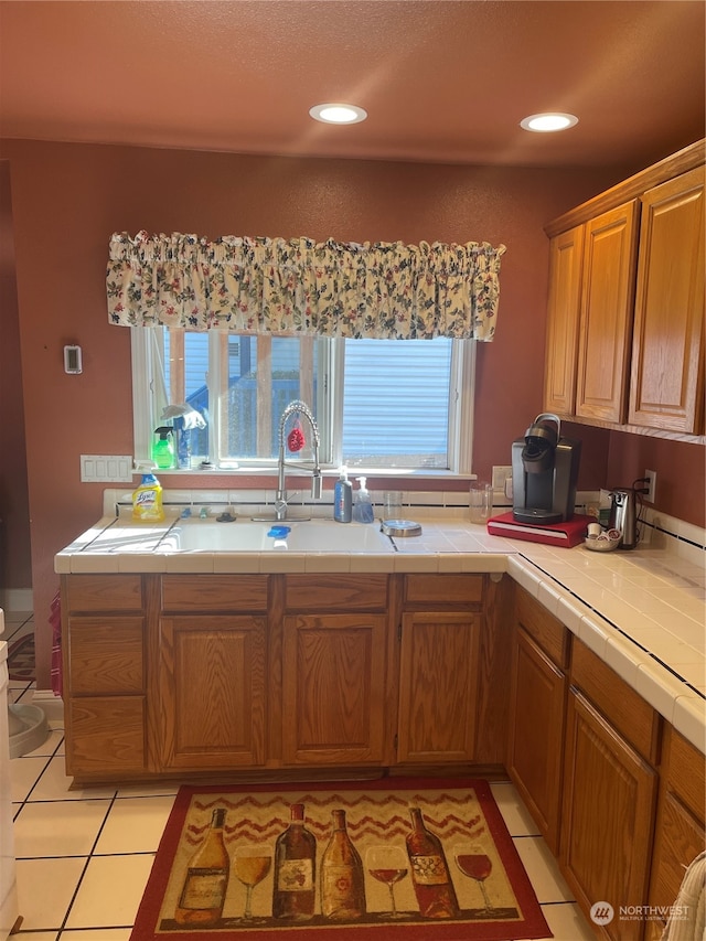 kitchen featuring light tile patterned floors, tile countertops, and sink