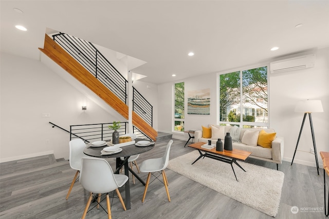 dining space featuring a wall mounted AC and wood-type flooring