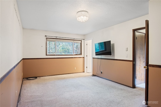 unfurnished room featuring light carpet and a textured ceiling