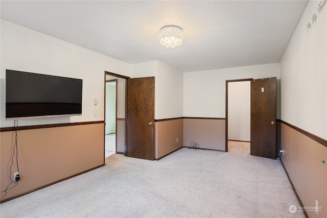 empty room with light colored carpet and a textured ceiling