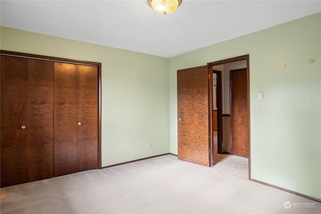 unfurnished bedroom with a closet, light colored carpet, and a textured ceiling