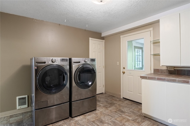 laundry area with washer and clothes dryer and a textured ceiling