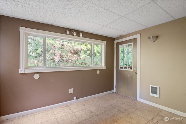 unfurnished room featuring heating unit and a drop ceiling