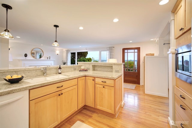 kitchen featuring stainless steel microwave, sink, light brown cabinets, white dishwasher, and light wood-type flooring