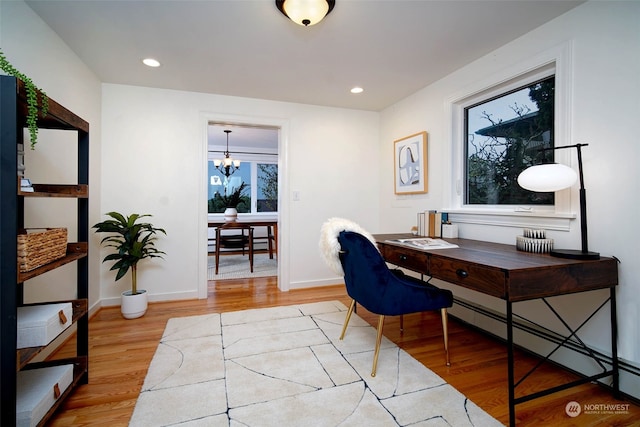 home office featuring light hardwood / wood-style floors, a baseboard heating unit, and a notable chandelier