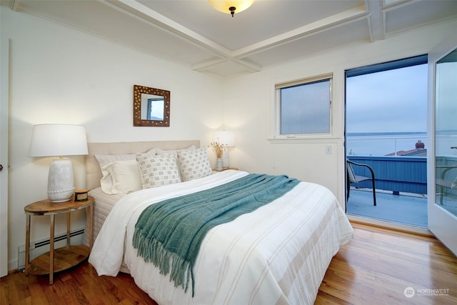 bedroom featuring baseboard heating, hardwood / wood-style floors, and access to outside