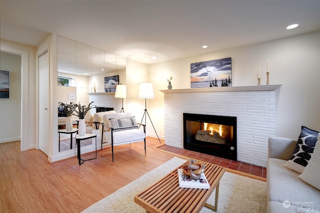 living room with wood-type flooring and a brick fireplace