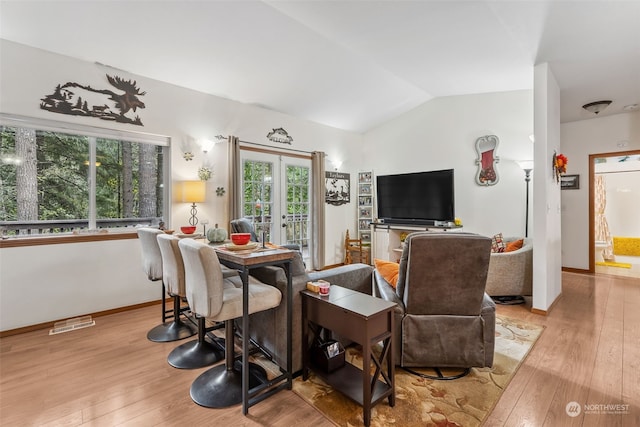 living room with lofted ceiling, light wood-type flooring, and french doors