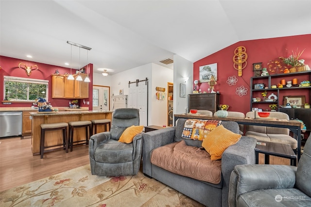 living room with a barn door, light hardwood / wood-style flooring, and lofted ceiling