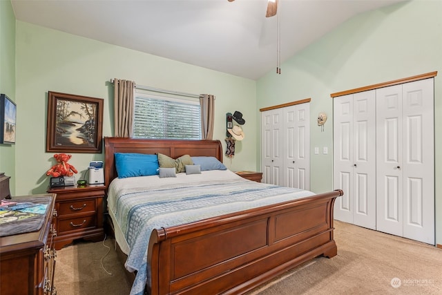 carpeted bedroom with two closets, ceiling fan, and lofted ceiling