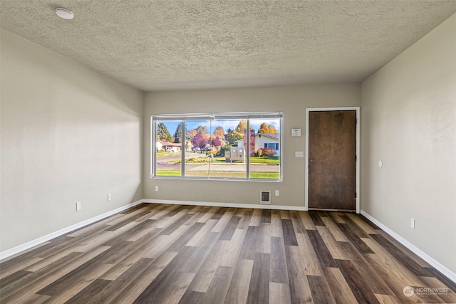 empty room featuring a textured ceiling and dark hardwood / wood-style flooring