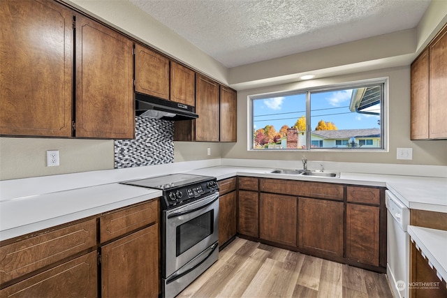 kitchen featuring sink, stainless steel appliances, backsplash, light hardwood / wood-style floors, and a textured ceiling