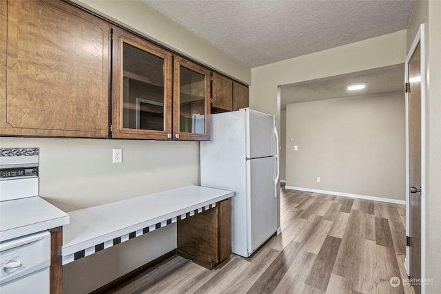 kitchen featuring a textured ceiling, white appliances, and light wood-type flooring