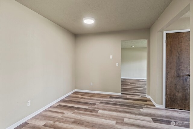 unfurnished room featuring light wood-type flooring and a textured ceiling