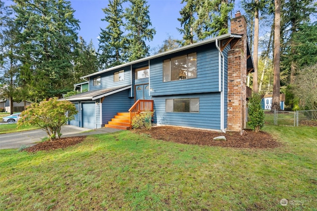 raised ranch featuring a garage and a front yard