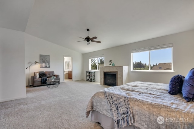 bedroom featuring lofted ceiling, light colored carpet, ceiling fan, ensuite bath, and a tile fireplace