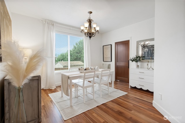 dining area with wood-type flooring and an inviting chandelier