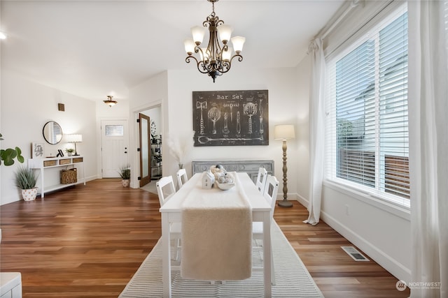 dining space with an inviting chandelier, baseboards, visible vents, and wood finished floors