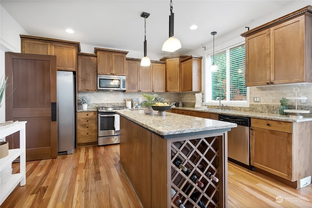 kitchen with a center island, backsplash, light wood-type flooring, appliances with stainless steel finishes, and decorative light fixtures