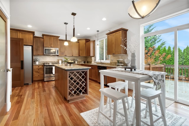 kitchen with tasteful backsplash, a healthy amount of sunlight, hanging light fixtures, and stainless steel appliances