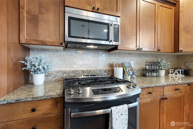 kitchen with stainless steel appliances, light stone counters, and tasteful backsplash